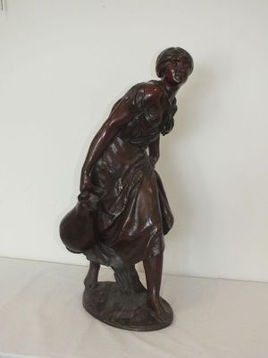 une statue représentant une femme tenant un sac sur une étagère