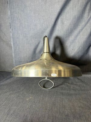 une vieille lampe à plaque en laiton, fixée à un support métallique, posée sur un canapé gris