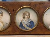 three miniature portraits of a man and a woman are on display