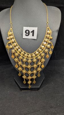 un collier en or sur un mannequin de vitrine, avec une étiquette de prix