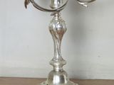 a silver candelab with two birds on it on a table