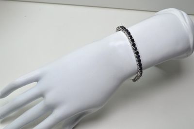 bracelet orné de diamants noirs et blancs, présenté sur la main d'un mannequin