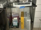 un chat assis dans une cage posée sur une étagère dans une cuisine