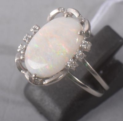 Une bague en oplite et diamant est posée sur une pierre noire