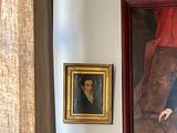 a picture of a man standing in a room with a painting on the wall