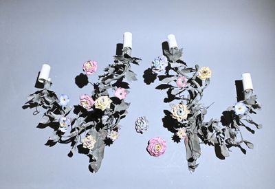 two wall sconces with flowers and leaves on them