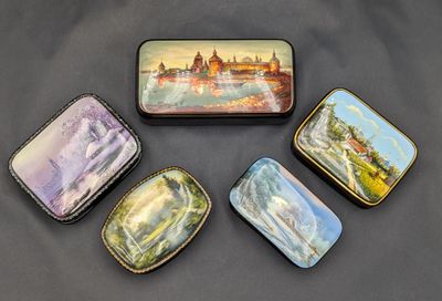 quatre boîtes ornées de peintures, posées sur une surface noire
