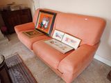un canapé rose sur lequel sont posés deux tableaux, dans un salon