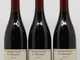 trois bouteilles de vin rouge sont alignées sur une surface réfléchissante