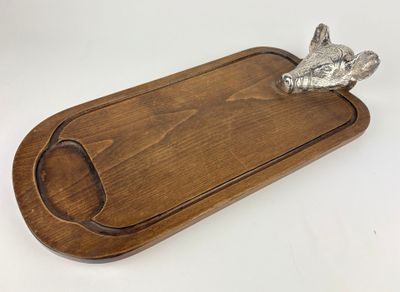 a close up of a wooden cutting board with a metal animal on it