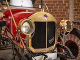 a red and gold car parked in front of a brick wall