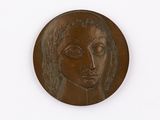 une image représentant un médaillon en bronze orné du visage d'une femme