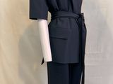 Le costume est noir et comporte une ceinture à la taille.