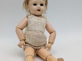 a wooden doll sitting on a white surface with a white background