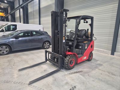 a forklift in a warehouse with a car in the background