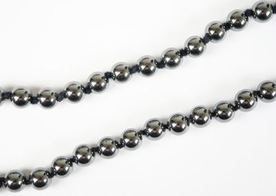 a close up of a black beaded necklace on a white background