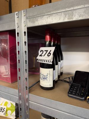 bottles of wine on a shelf in a store with price tags on them