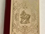 an old book with a gold design on it sitting on a white surface