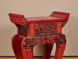 un petit tabouret rouge posé sur un plancher en bois