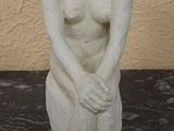 a white statue of a woman sitting on a black table