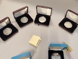 five silver coins in small cases on a table