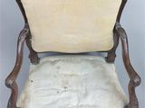 an old chair with a white upholstered seat and a wooden frame