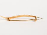 a close up of a gold hair pin on a white background
