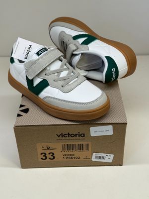 des baskets blanches et vertes à velcro, avec des semelles en velcro, posées sur une boîte en carton