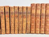 six vieux livres sont alignés sur une surface blanche
