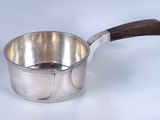 a silver saucepan with a wooden handle on a white surface