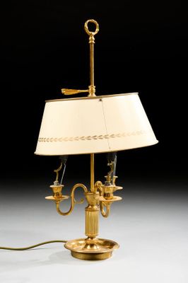 an antique brass table lamp with a white shade on a black background