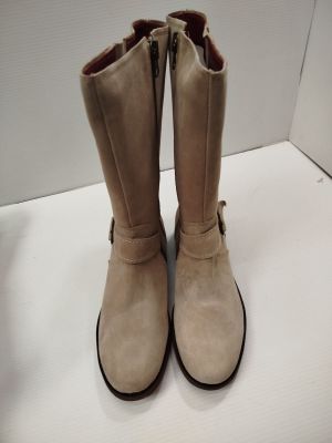 une paire de bottes beiges posée sur une table blanche