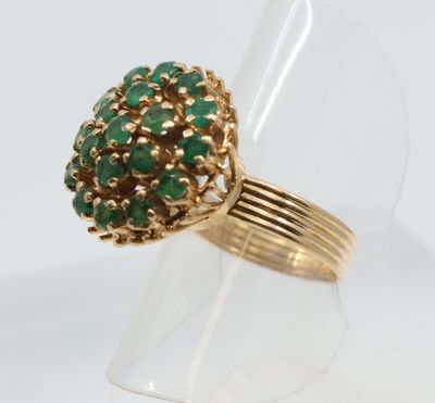Gros plan sur une bague en or ornée de pierres vertes