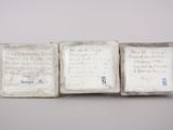three small white tiles with writing on them sitting on a table