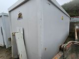 a white box sitting on the ground next to a dumpster