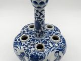 a blue and white vase with a candle holder on it