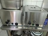 un plan de travail en acier inoxydable sur lequel sont posés deux casseroles et poêles