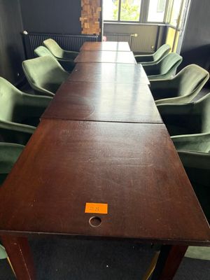 une longue table avec des chaises vertes et une étiquette jaune posée dessus