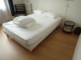 a bed with white sheets and pillows in a small room