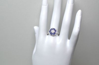 une main blanche ornée d'une bague bleue et blanche