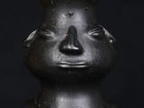 a black vase that has a face on it