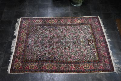 un tapis posé au sol, avec un vase de fleurs en arrière-plan