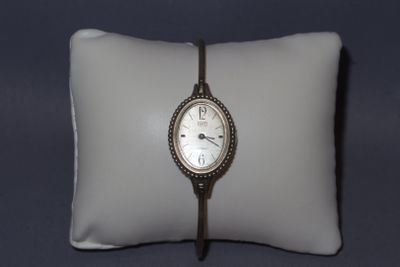 une montre posée sur un oreiller, elle-même posé sur un autre oreiller