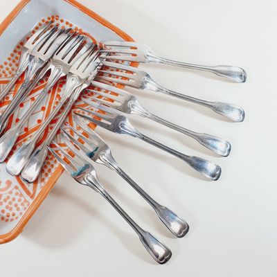 several forks and spoons are arranged on an orange and white plate