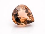 a close up of a faceted brown diamond on a white surface