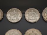 six different types of silver coins on display in a glass case
