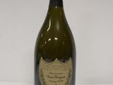 une vieille bouteille de vin posée sur une table blanche