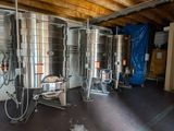 several stainless steel tanks are lined up in a large room