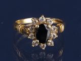 un gros plan d'une bague en or sertie d'une pierre noire entourée de diamants blancs