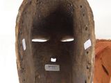 a wooden mask hanging on a wall next to a pair of shoes
